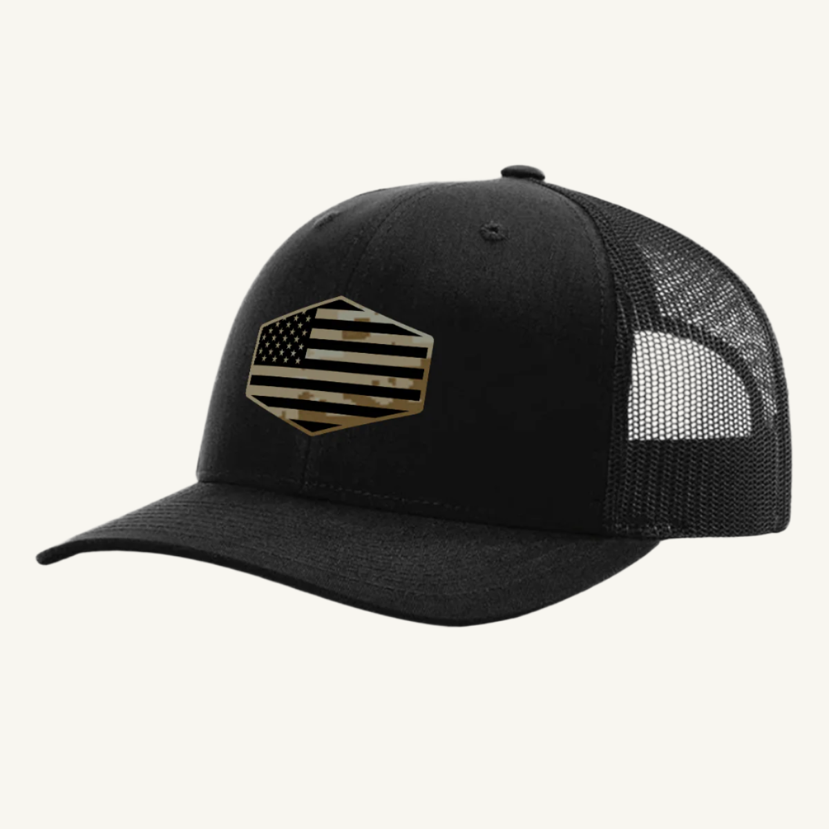 A black trucker hat with a digicam acrylic patch featuring the US flag in a desert storm camouflage pattern on the front.