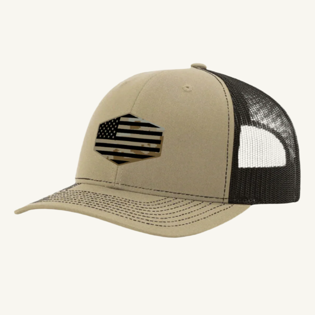 A khaki and brown trucker hat with a digicam acrylic patch featuring the US flag in a desert storm camouflage pattern on the front.