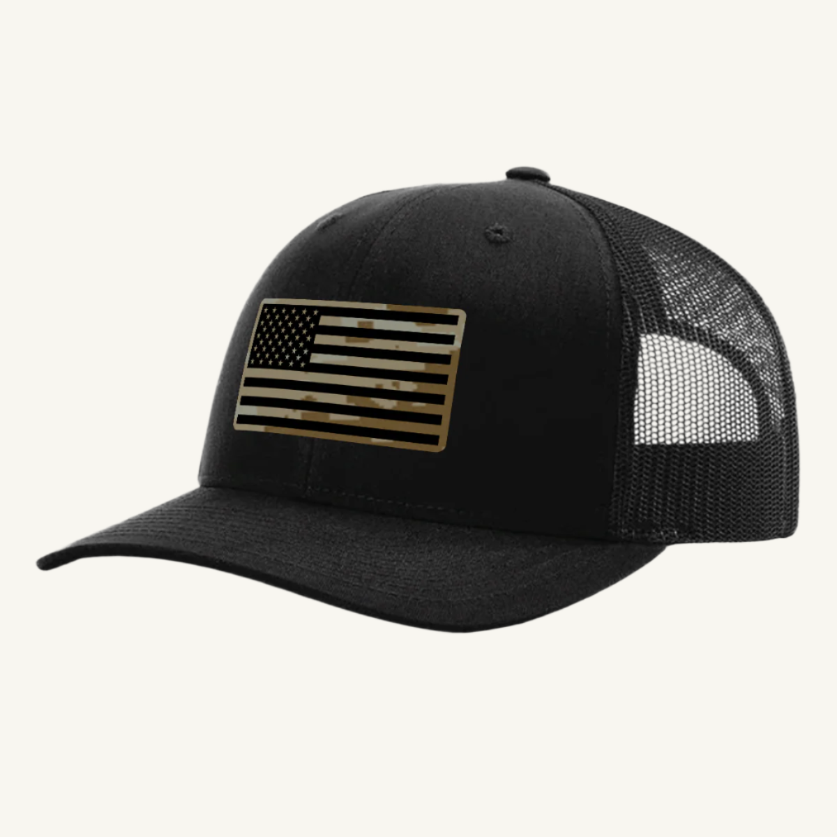 A black trucker hat with a digicam acrylic patch featuring the US flag in a desert storm camouflage pattern on the front.