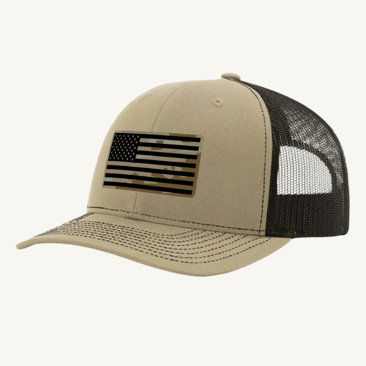 A khaki and brown trucker hat with a digicam acrylic patch featuring the US flag in a desert storm camouflage pattern on the front.