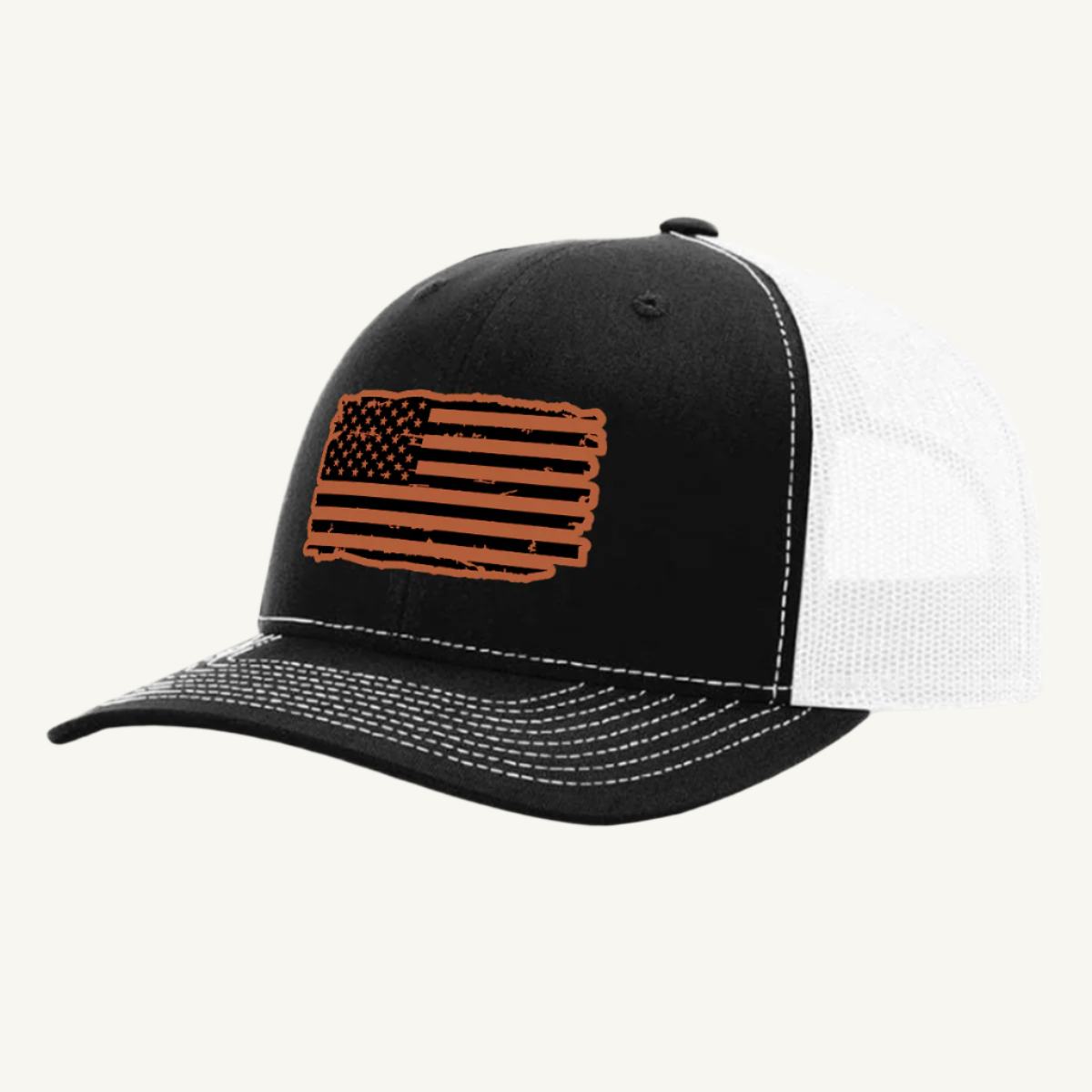 A black and white trucker hat with a distressed American flag design on the front, featuring a leatherette patch.