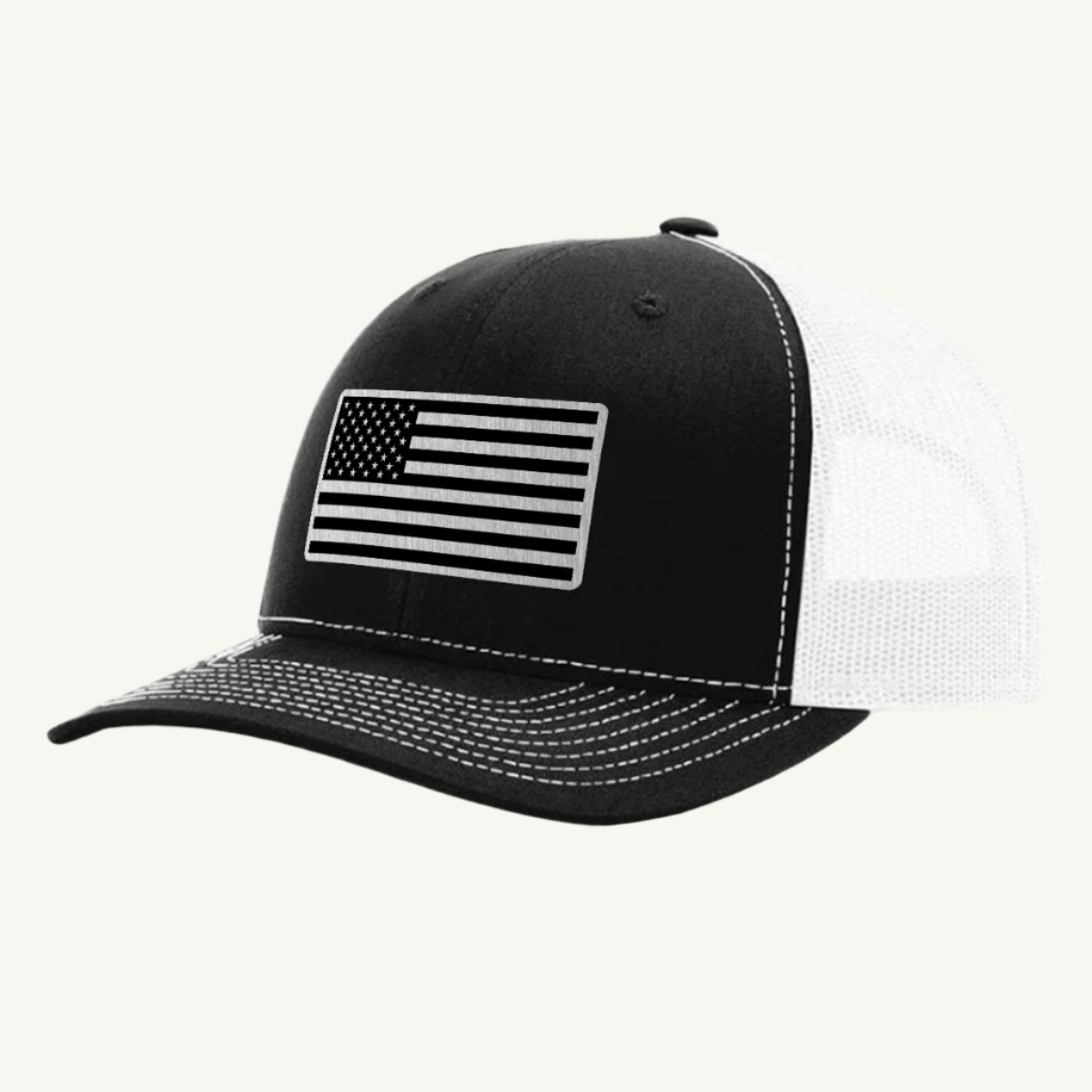 A black and white trucker hat with a stainless steel acrylic patch featuring an American flag design on the front.
