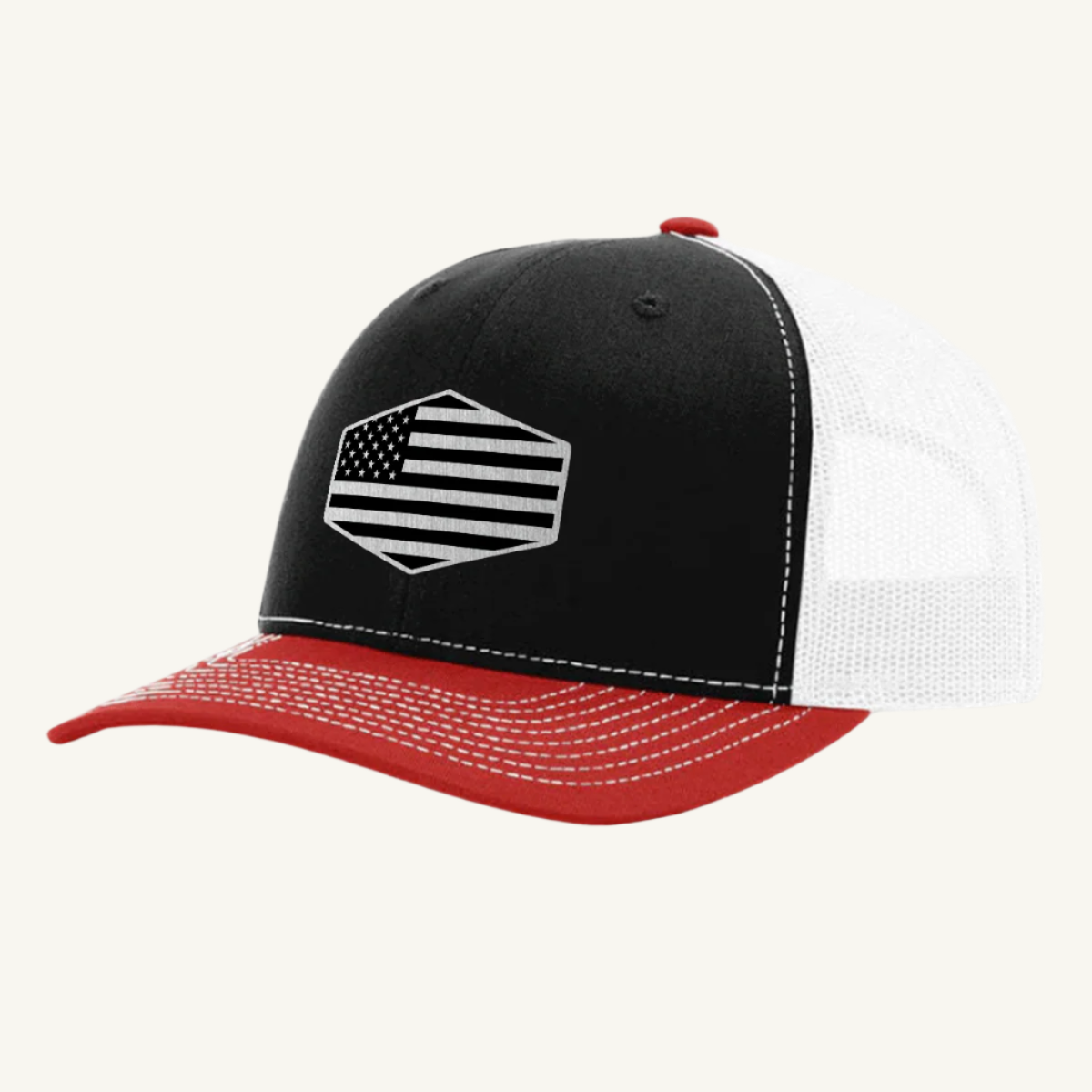 A red, black, and white trucker hat with a stainless steel acrylic patch featuring an American flag design on the front.