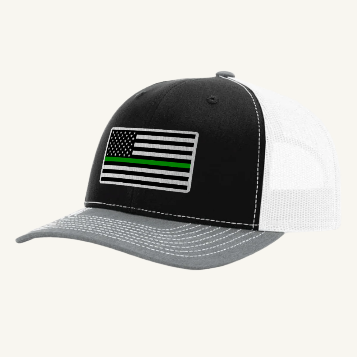 A black, gray, and white trucker hat with an acrylic patch on the front displaying the Thin Green Line American Flag.