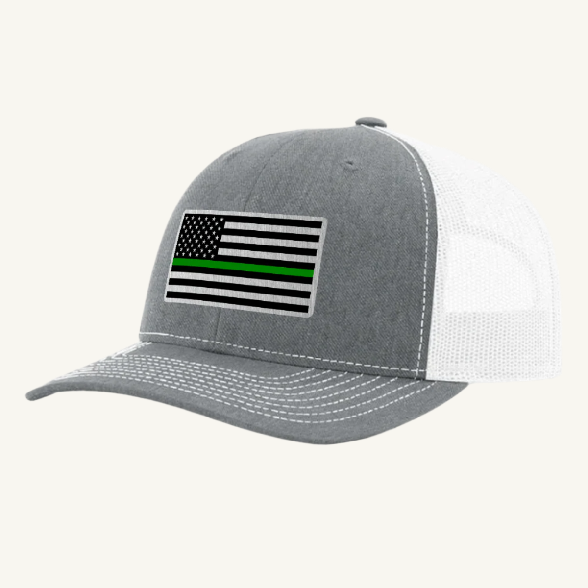 A heather gray trucker hat with an acrylic patch on the front displaying the Thin Green Line American Flag.
