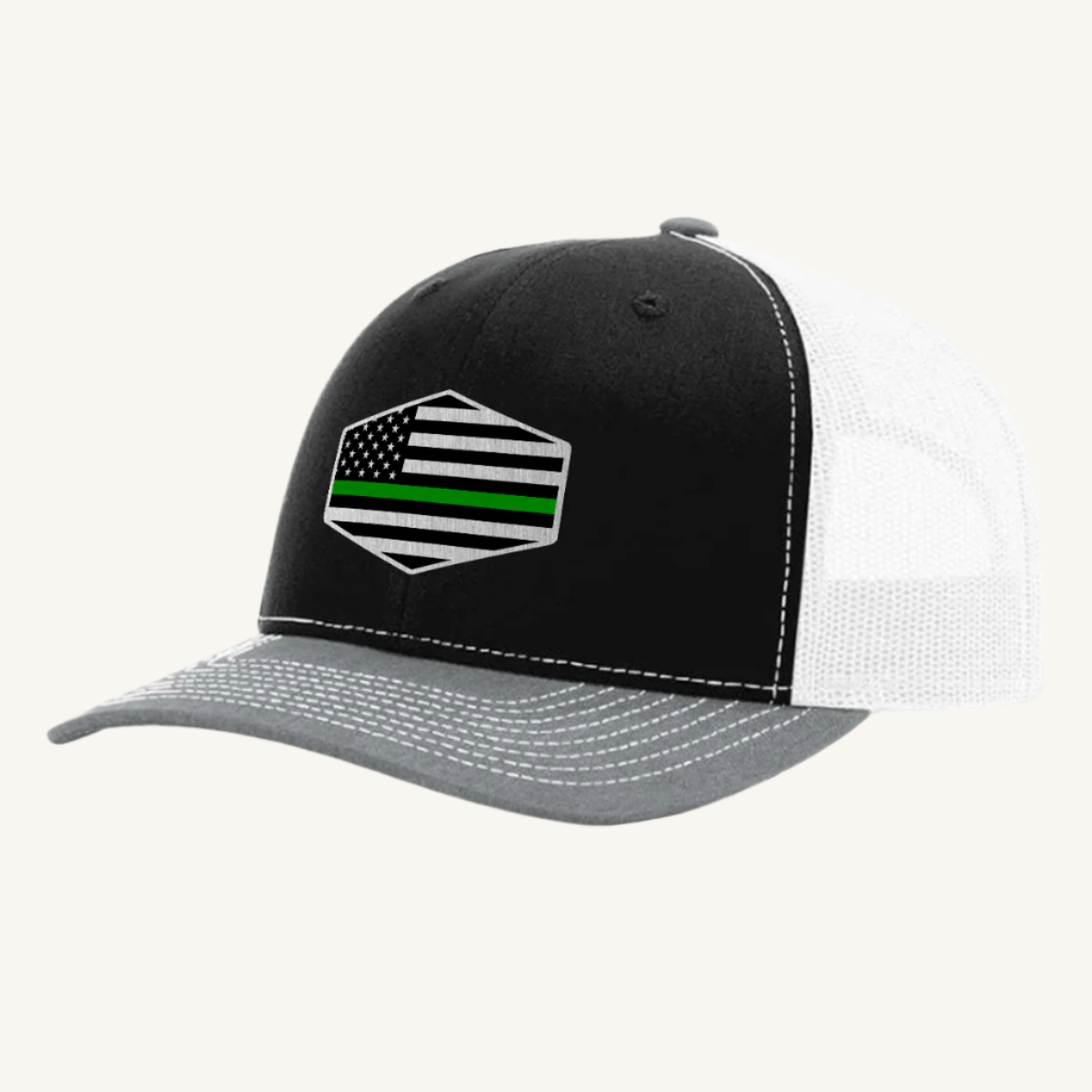A black, gray, and white trucker hat with an acrylic patch on the front displaying the Thin Green Line American Flag.
