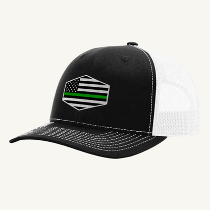 A black and white trucker hat with an acrylic patch on the front displaying the Thin Green Line American Flag.