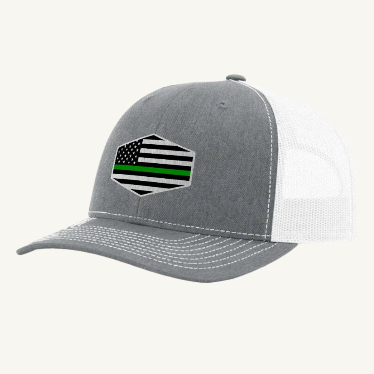 A heather gray trucker hat with an acrylic patch on the front displaying the Thin Green Line American Flag.