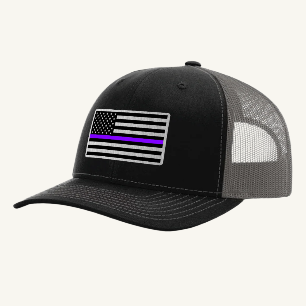 A black and gray trucker hat with an acrylic patch on the front featuring the Thin Purple Line American Flag.