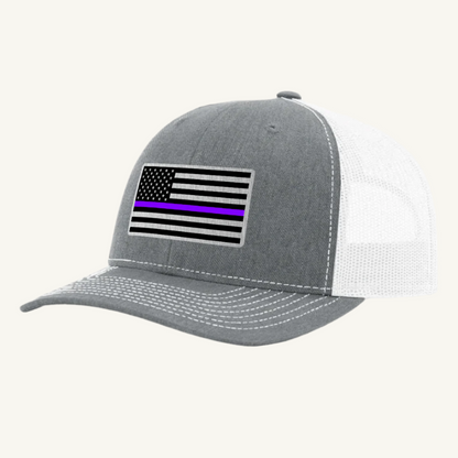 A heather gray and white trucker hat with an acrylic patch on the front featuring the Thin Purple Line American Flag.