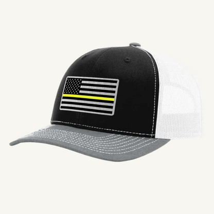 A black, heather gray, and white trucker hat with a thin yellow line American flag acrylic patch on the front.